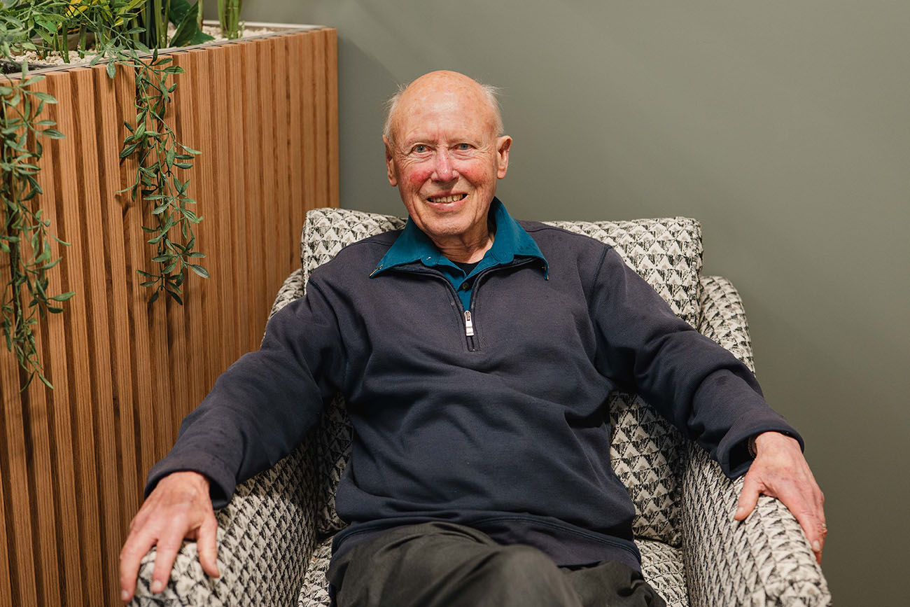 A portrait of Robin Kingston, sitting on a chair, smiling