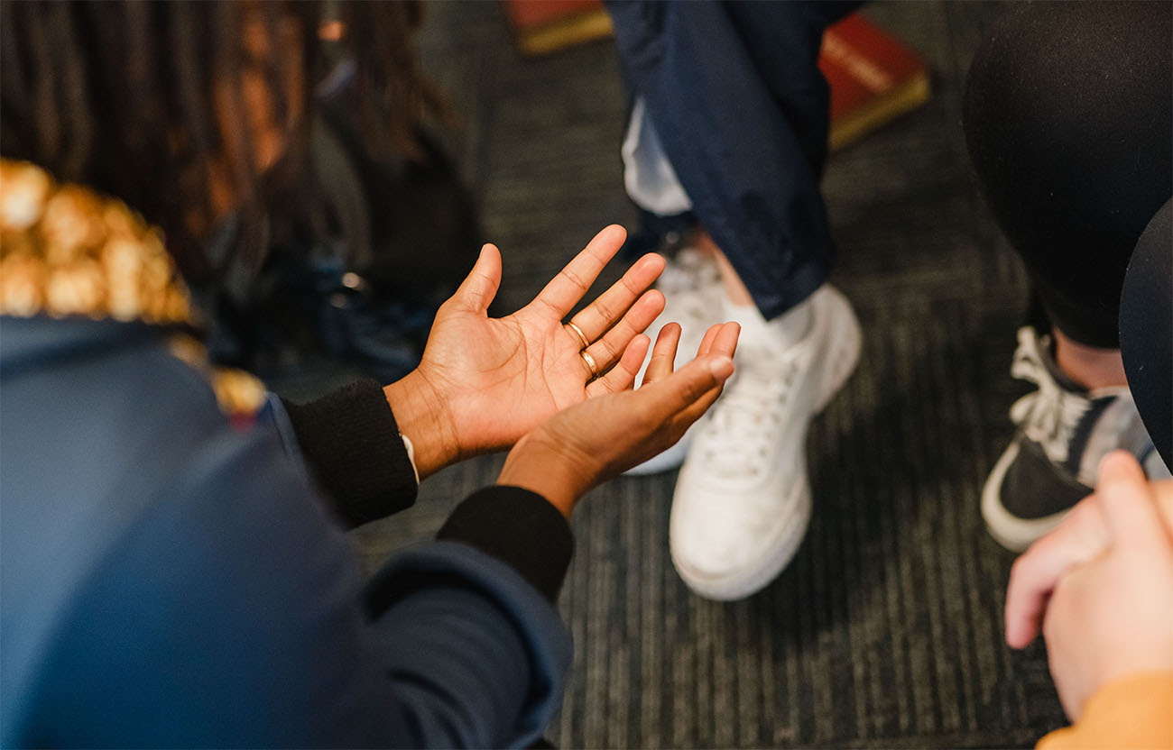 A woman with her hands facing palm up in prayer