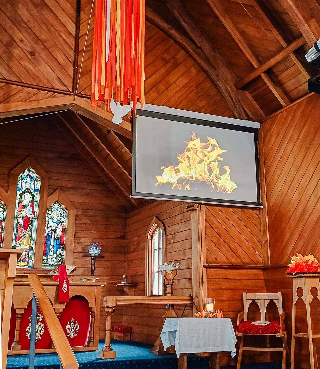 the interior of St Luke's church, wooden walls and ceilings, decorated with fire and dove symbols for Pentecost