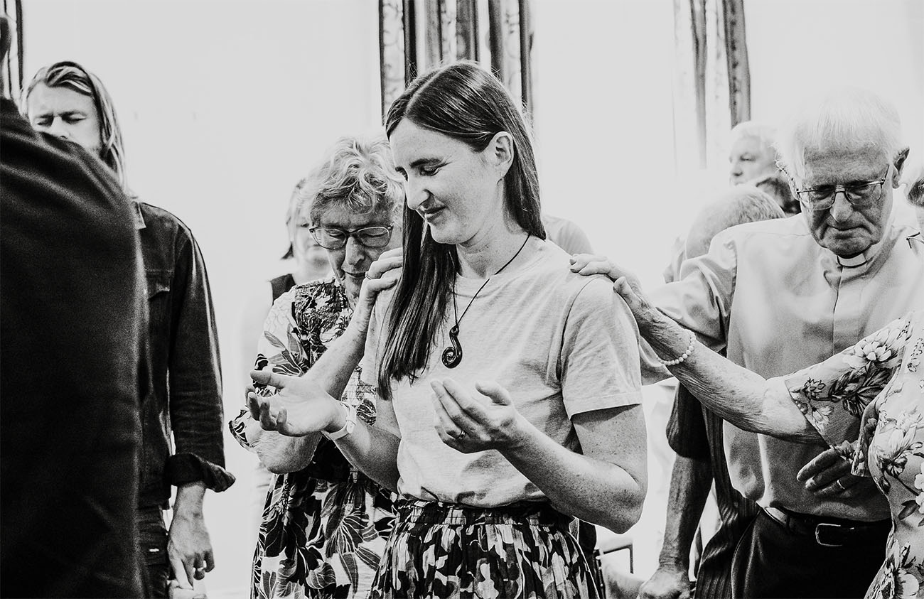 people gather around a woman to pray