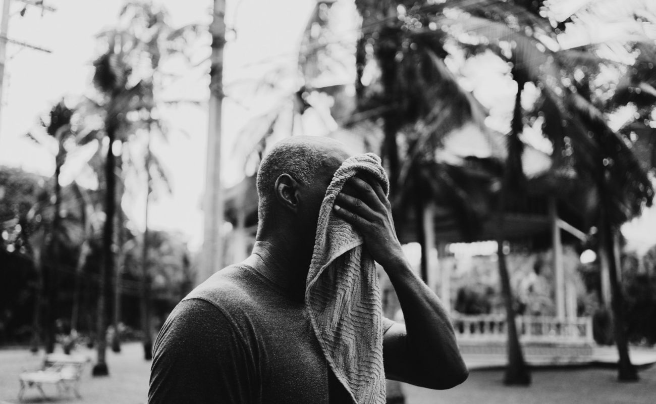 a man wipes sweat from his face with a towel