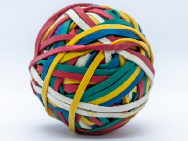 Close-up of a colorful rubber band ball made of intertwined red, blue, yellow, green, and white bands.