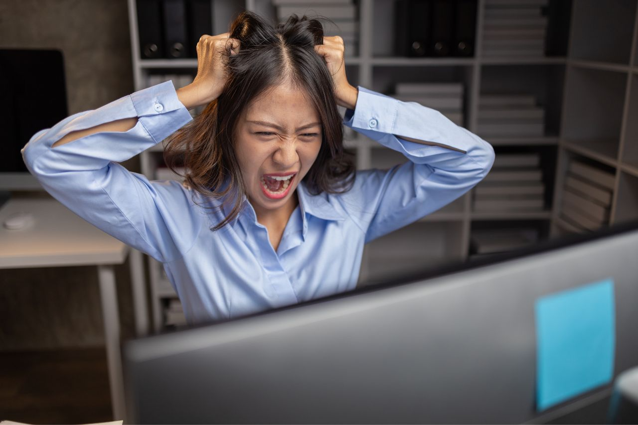 A frustrated employee is expressing her frustration in front of a computer screen.