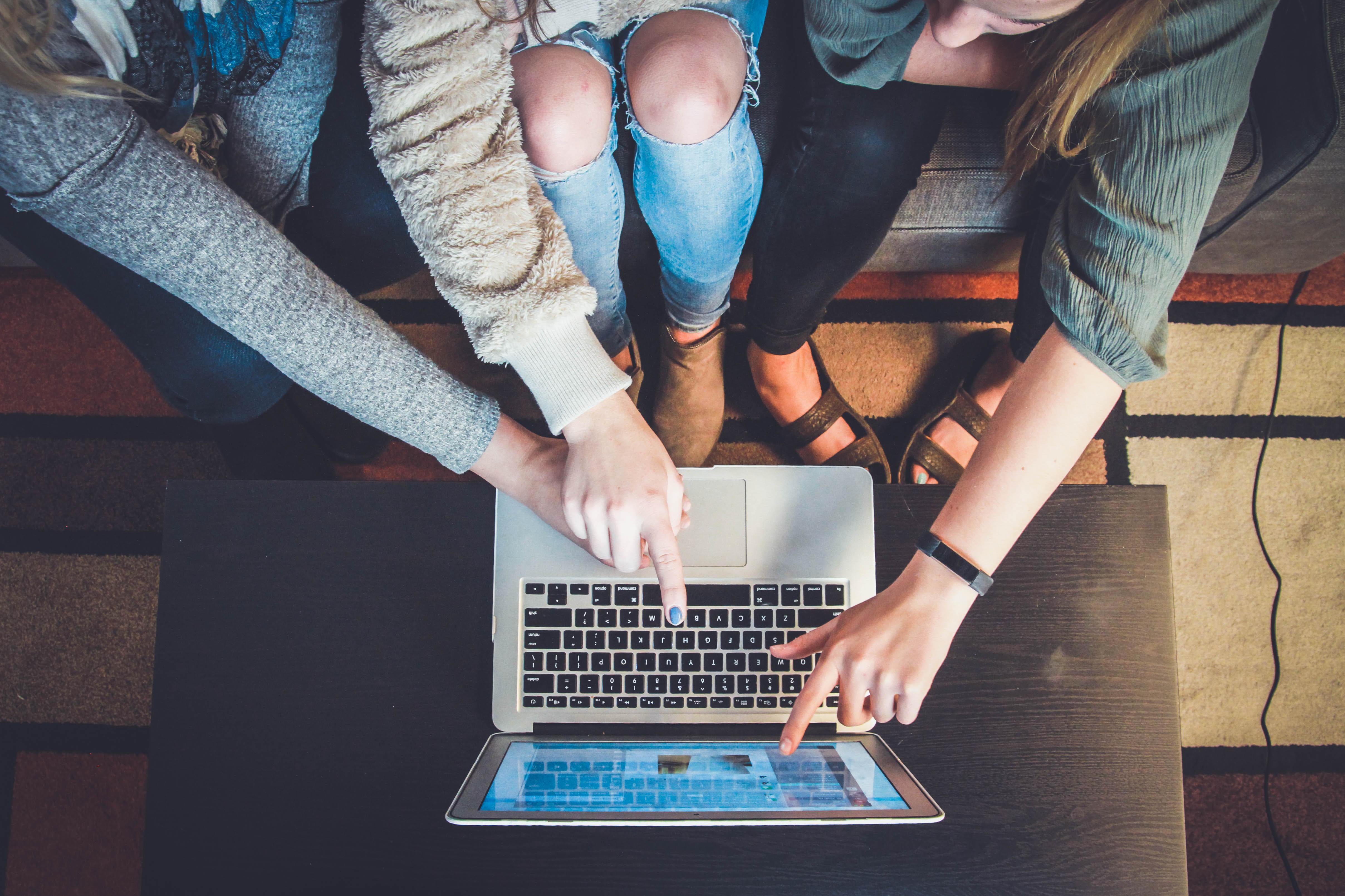 Three people hunched over a computer