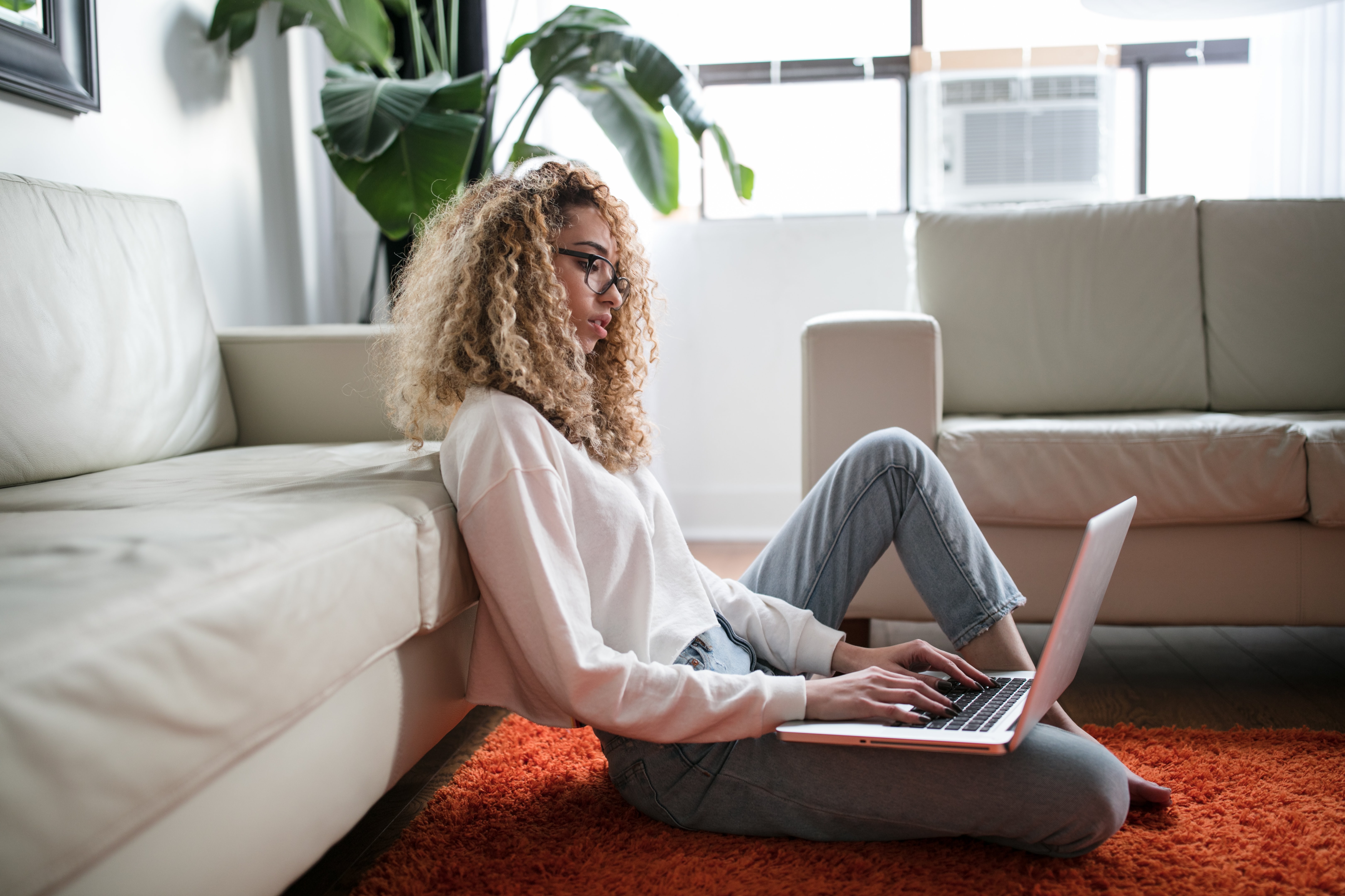 Curly haired girl sitting on floor on laptop