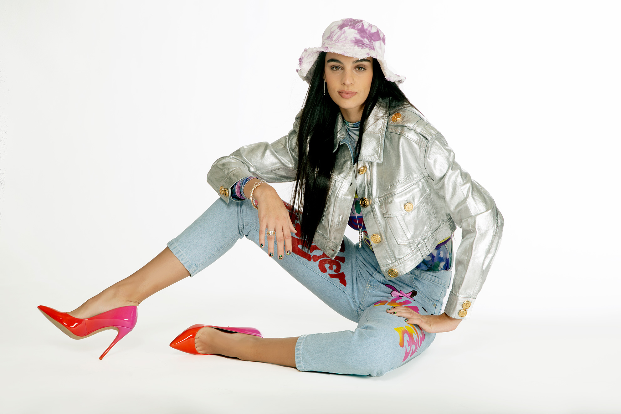 chamarra vaquera Balmain, playera con gráfico Desigual, top Versace Jeans Couture, jeans mom y sombrero bucket Wild & Alive, zapatillas Aldo, collar oso y pulsera carrusel Tous, pulsera Adolfo Dominguez, aretes y anillo de la colección bésame Tane - El Libro Amarillo