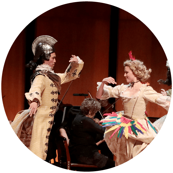 Two costumed performers—a man with a hat and a woman with a color skirt