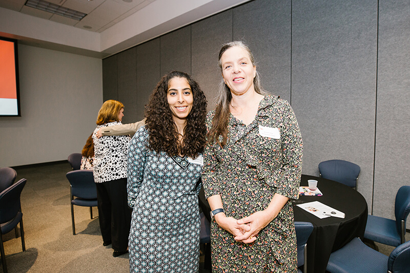 Two women stand next to one another, pictured from the waist up