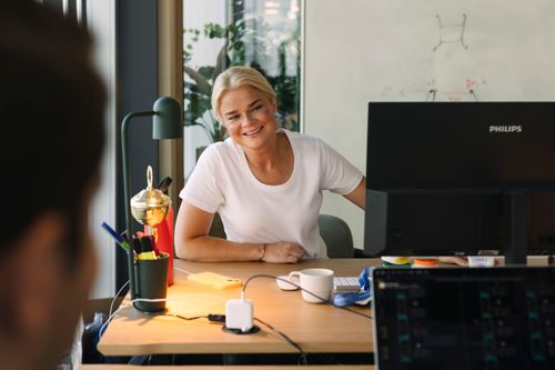 Two people talking to each other in front of laptop