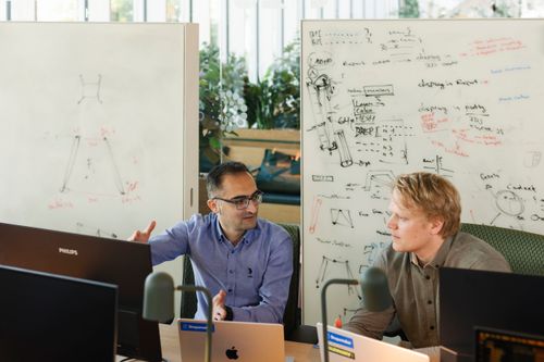 Two people talking in front of whiteboard