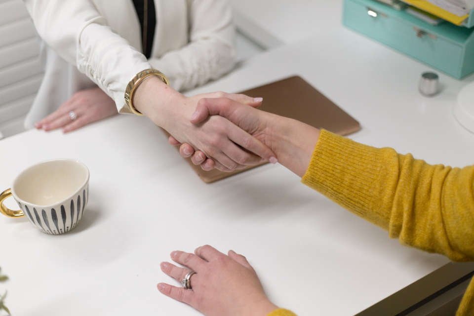Two professionals shaking hands across a table to close a business agreement