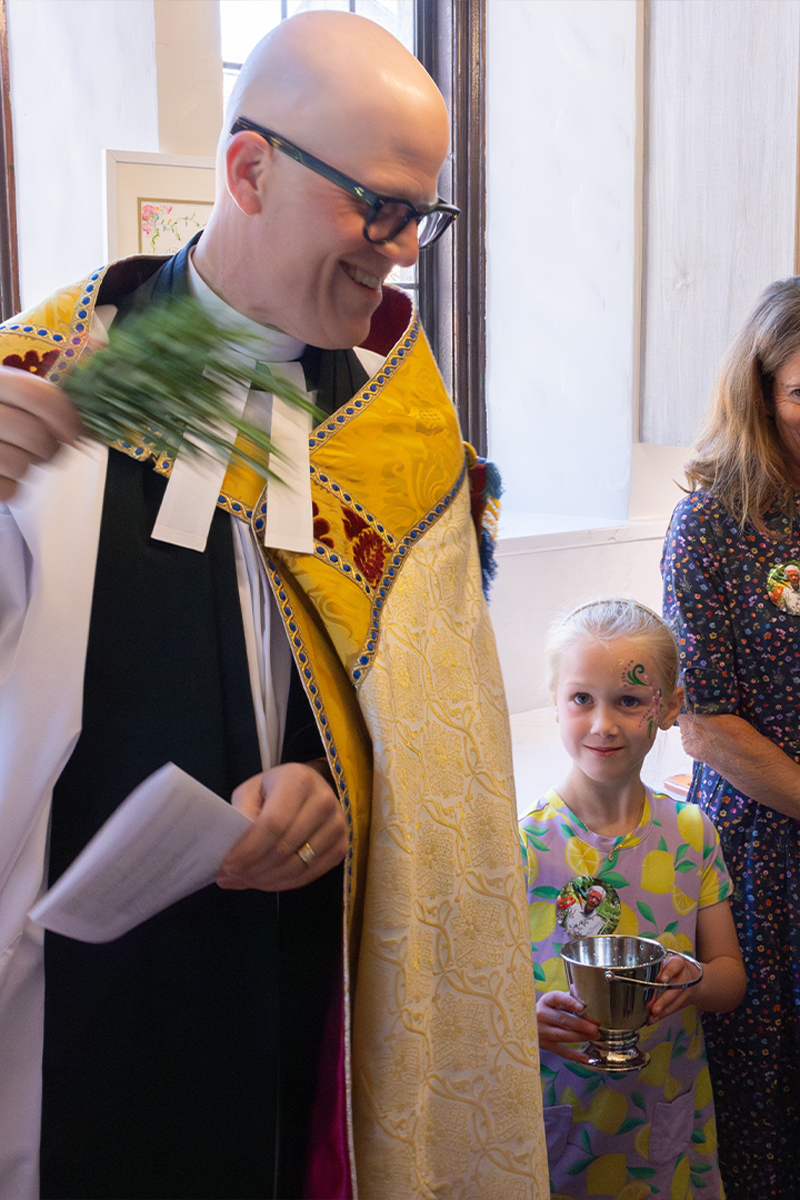 A priest with a rosemary sprig during the blessing of a space.