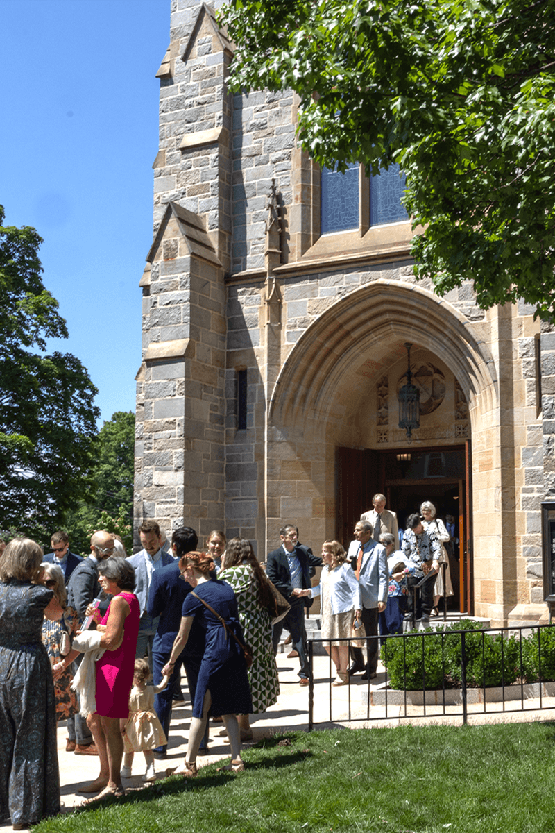 Church Exterior with people exiting the church on a sunny spring day.