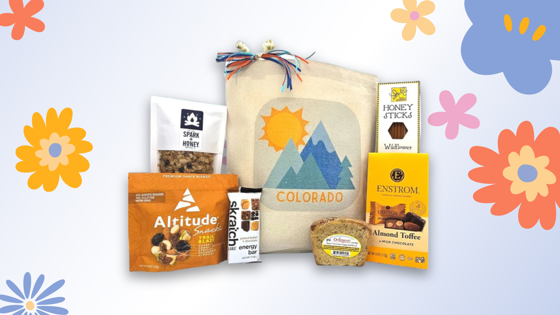 Mother's Day gift set with a mountain-themed tote bag and various Colorado-made snacks and sweets, decorated with colorful spring flowers.