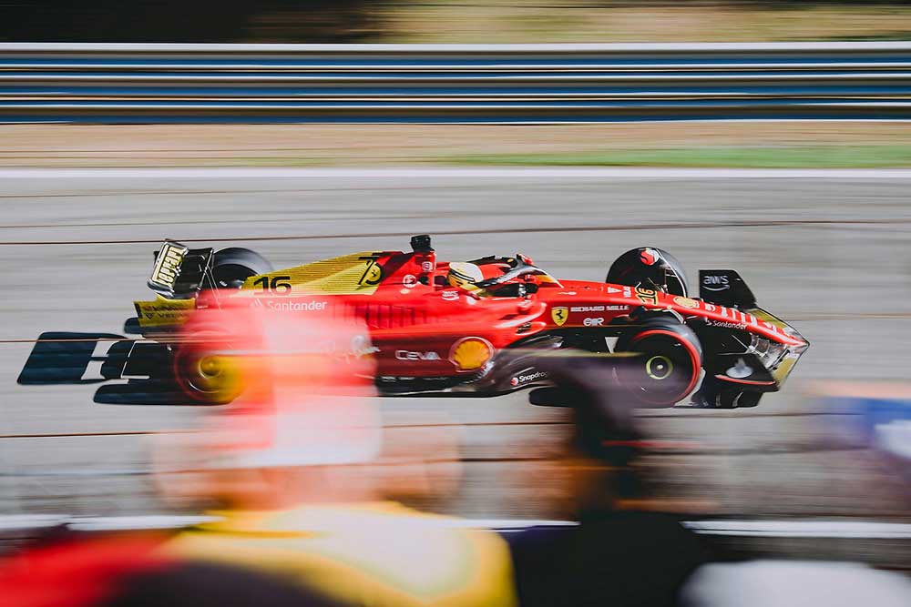 Red Formula 1 car races on a track. It's moving so fast that it's nearly a blur.