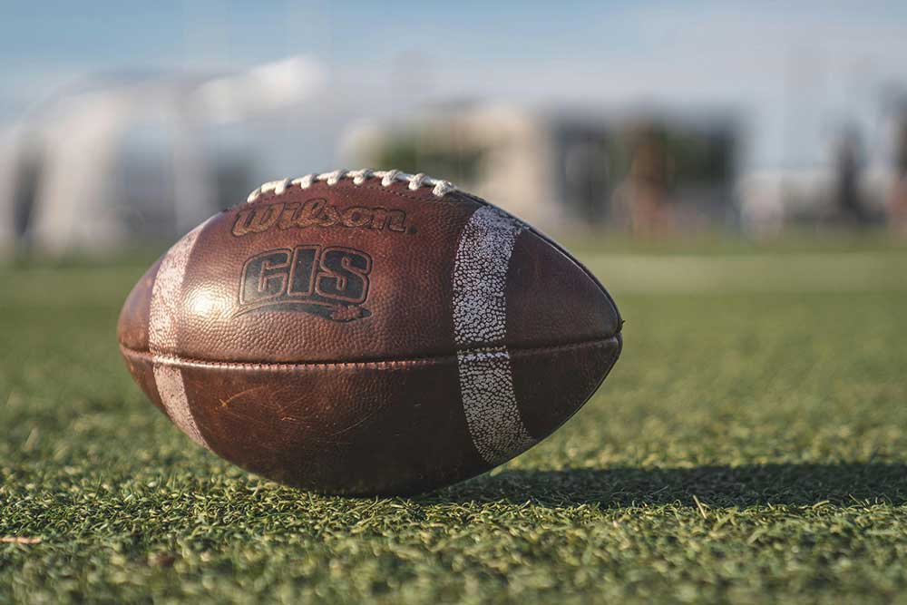 American football lies on a green field.