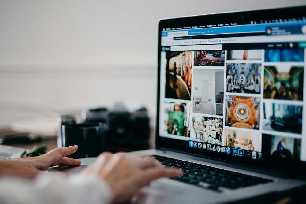 Person works on a laptop. The screen of the laptop shows a variety of still images.