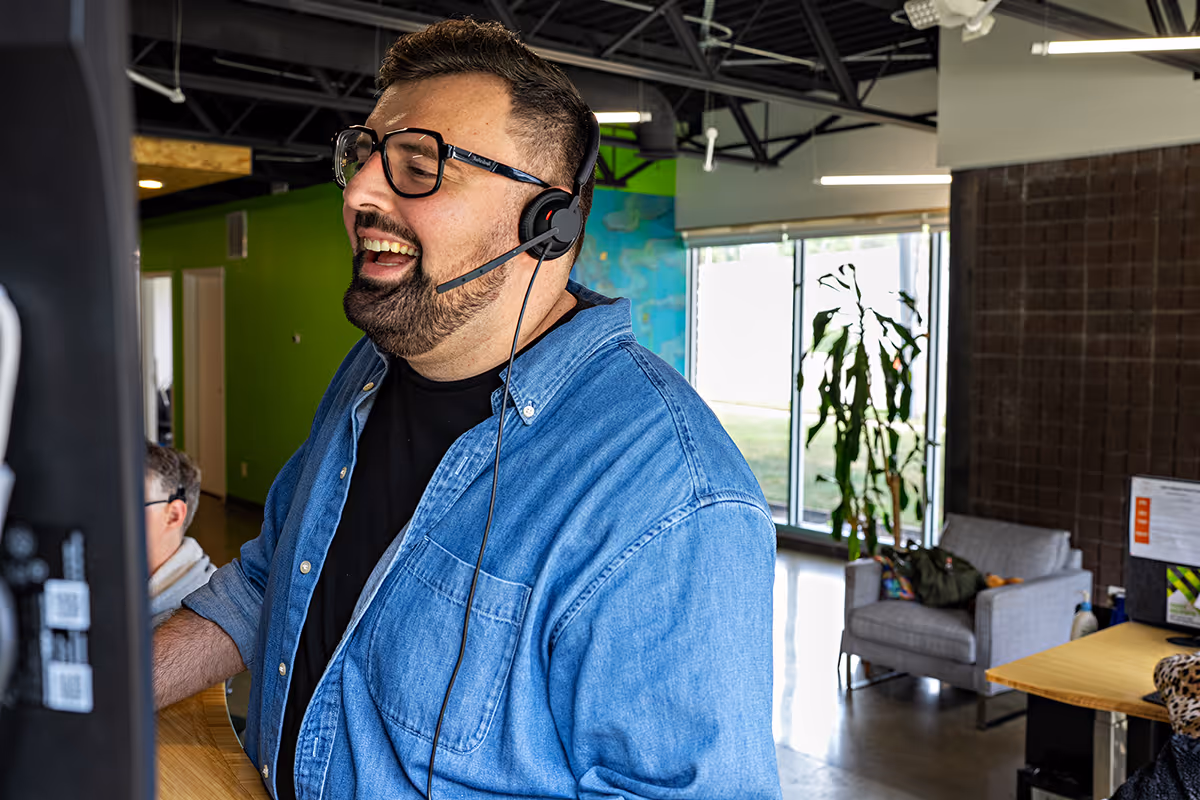Halil standing at his desk, smiling while talking on the phone