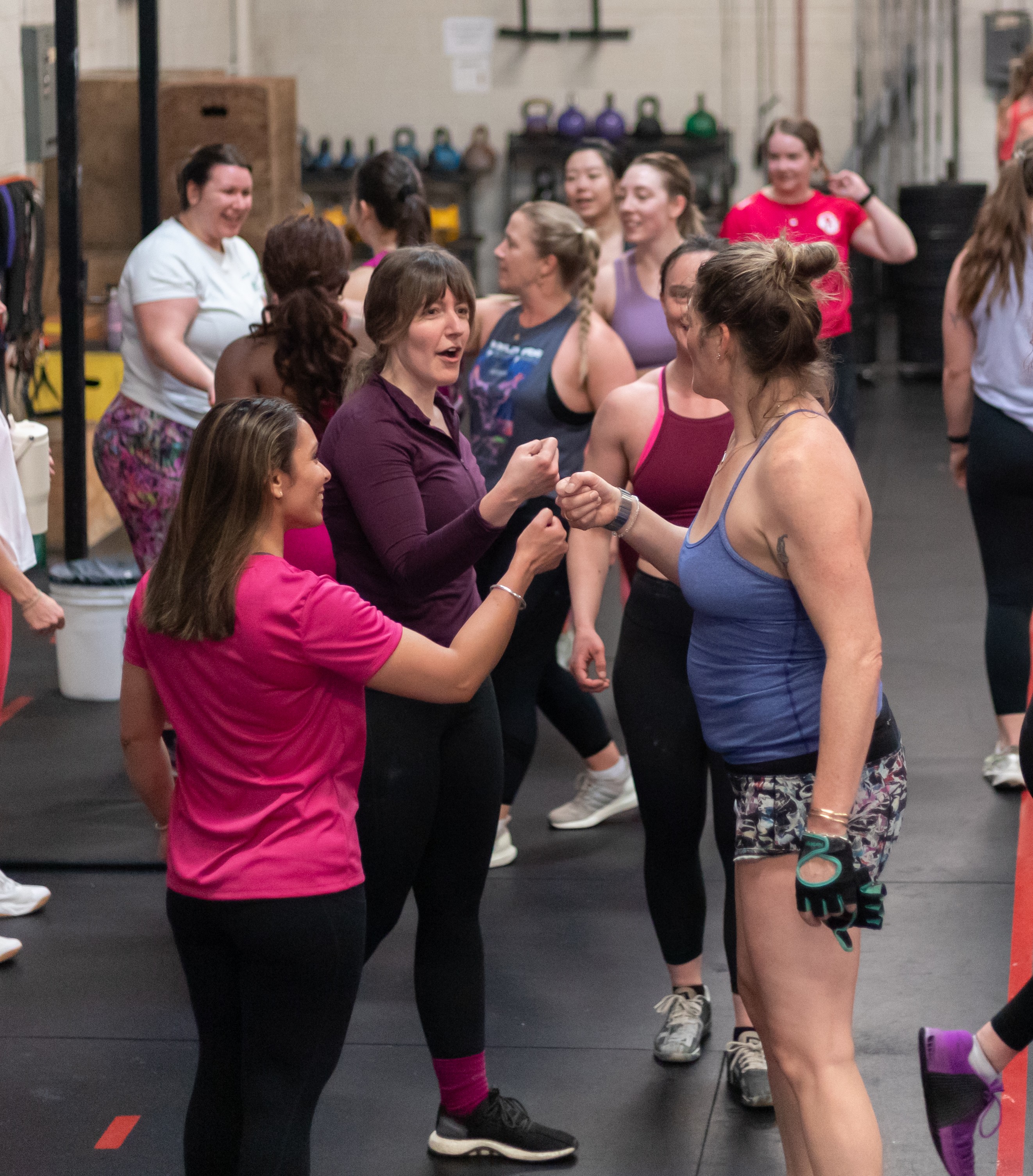 Three people exercising on stationary assault bikes in a gym setting.