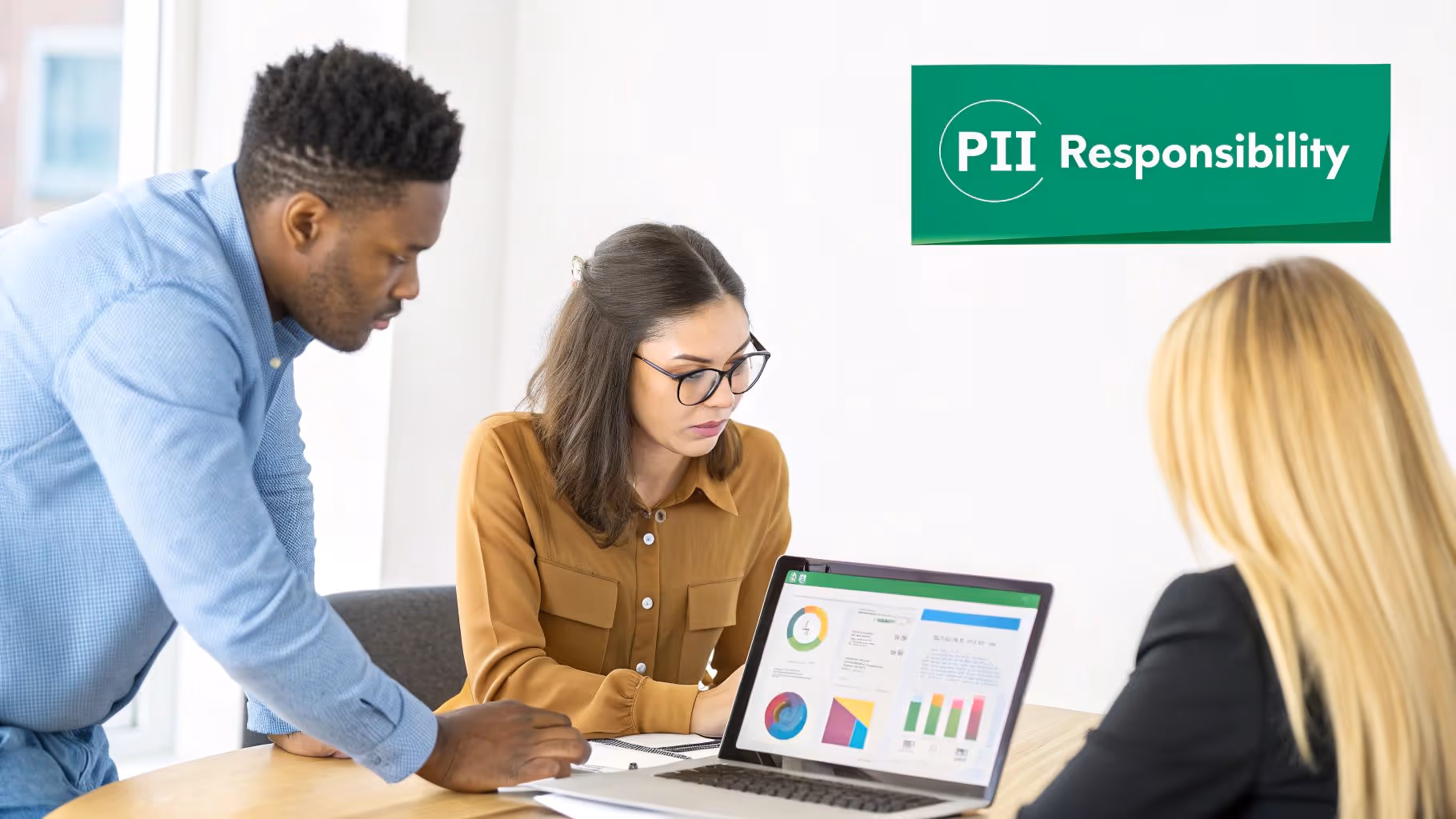 Three diverse colleagues analyze data charts on a laptop during an office meeting.