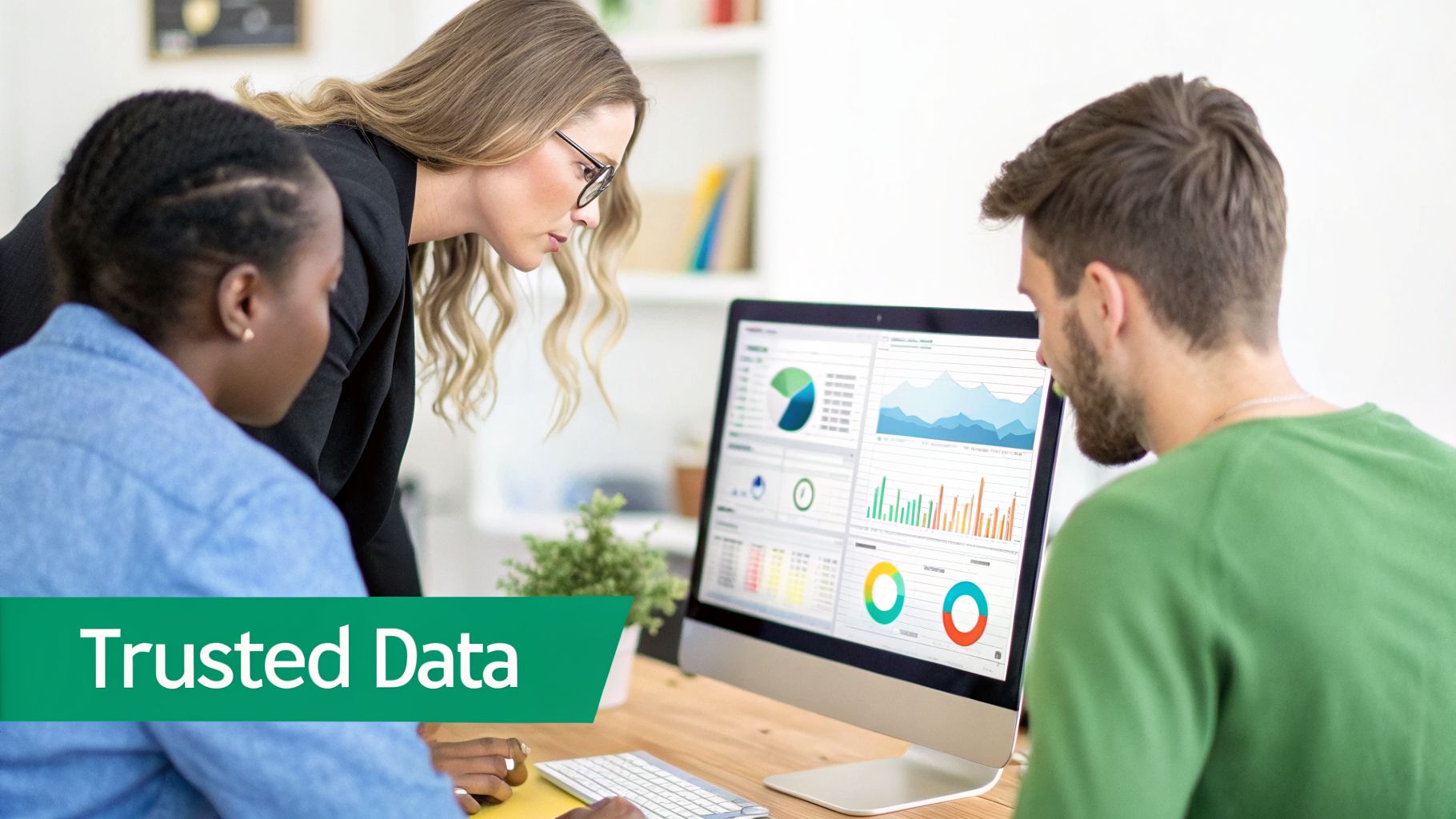 Three colleagues collaborate, reviewing data visualizations on a computer screen, emphasizing trusted data analysis.