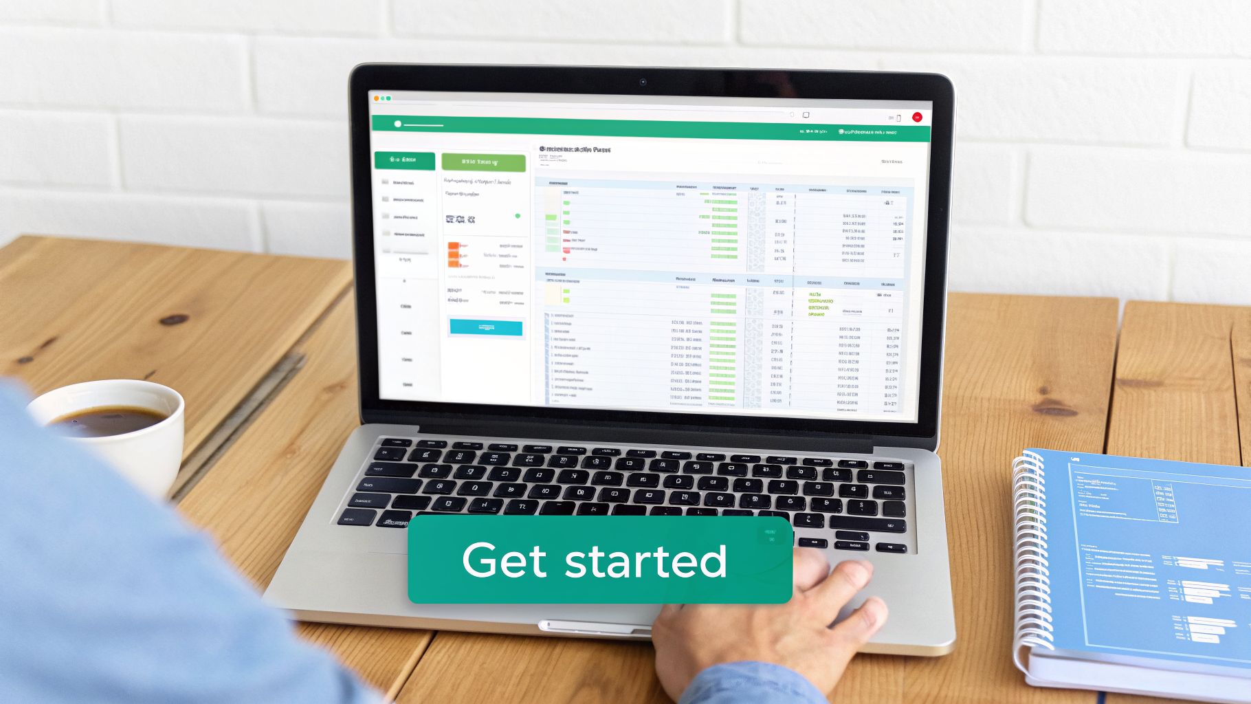 Person using a laptop displaying a data dashboard, with coffee and a notebook on a wooden desk.