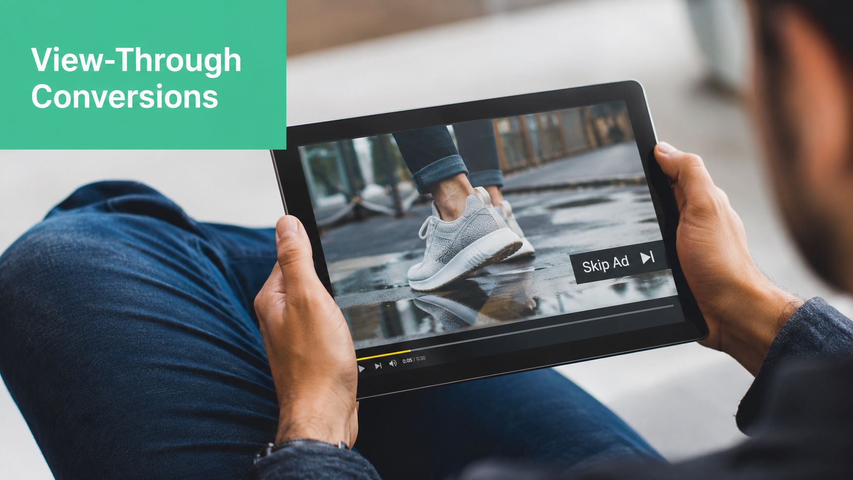 A person holding a tablet showing a video advertisement with a skip ad button overlay.