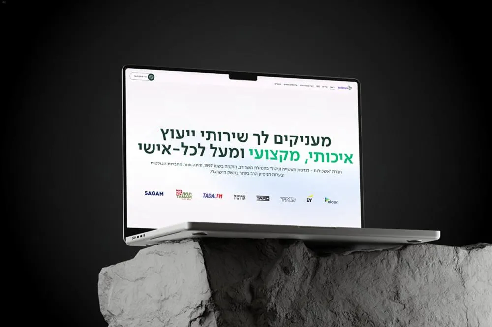 Laptop displaying a Hebrew website offering quality professional services and consulting, placed on a textured stone surface against a dark background.