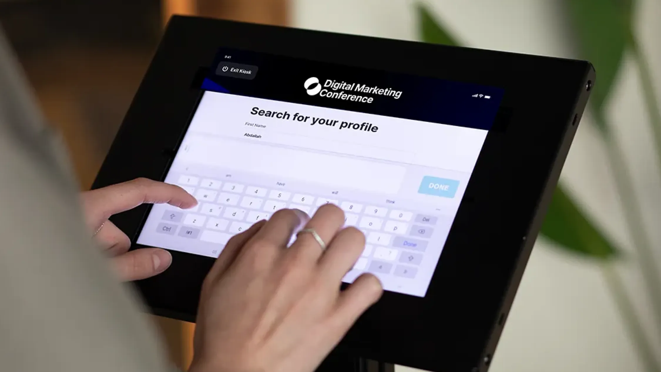 Photo illustration of a check-in kiosk scanning a QR badge with clear lanes, signage, and a live attendance dashboard on a nearby tablet.