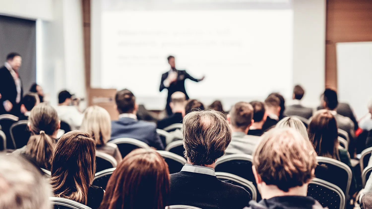 Event manager building a multi track conference agenda on a laptop, with color coded sessions, speaker photos, and attendee schedules visible on screen.