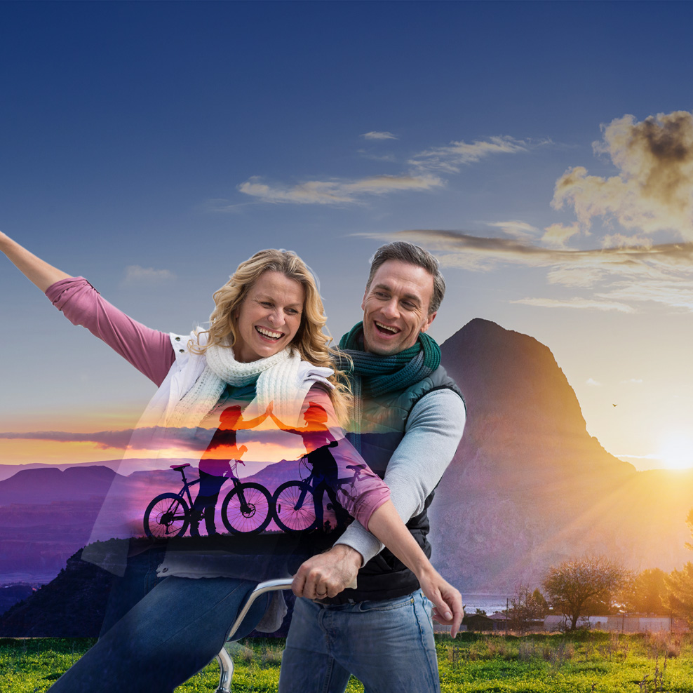A happy couple riding a bike.

