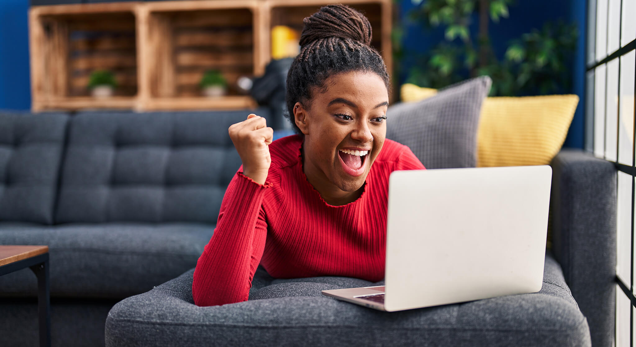 Young African American learner celebrating success on laptop.