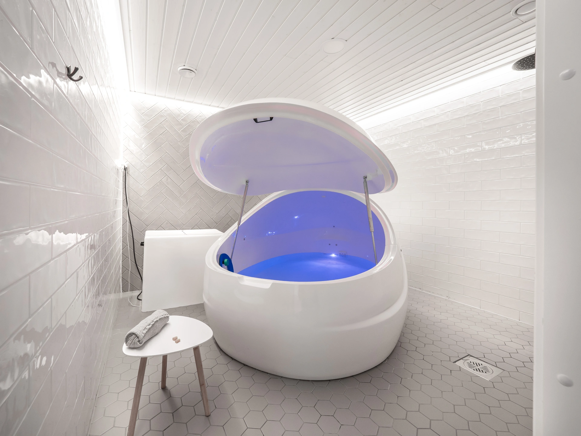 Valkoinen äänieristetty kelluntatankki sinisellä valaistuksella modernissa, valkoisessa laatoitetussa Oulu Floats Floasis kelluntahuoneessa. Rentoutuskellunta oulu. Rauhankatu Floats Tampere Floats Turku Floats Oulu Floats Floasis Palauttamo Rentouttava laine Rentoutuskellunta float oulu float tampere float turku.