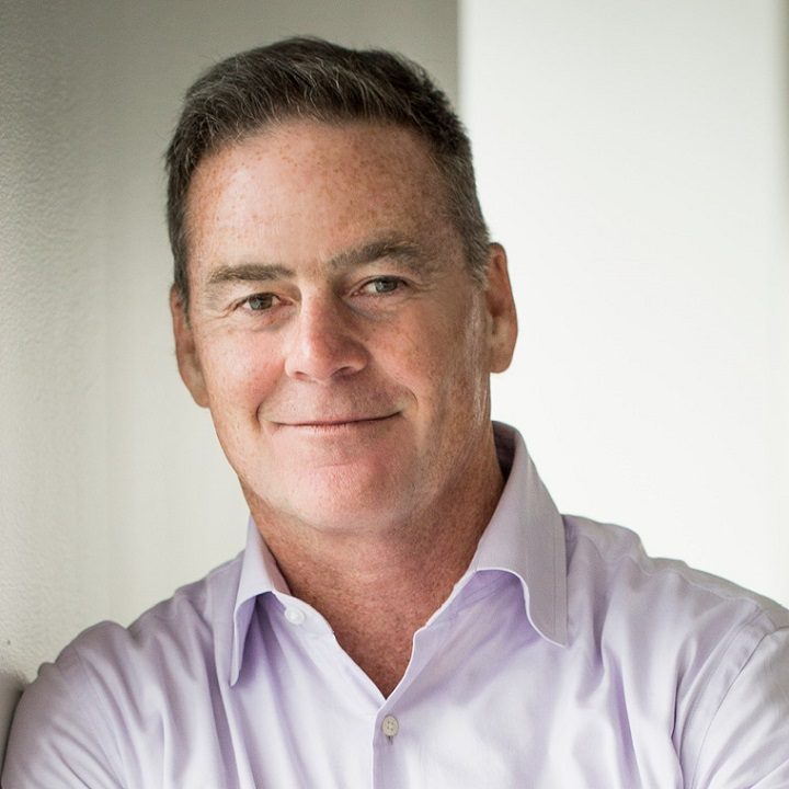 Man in purple shirt smiling at camera, professional headshot portrait