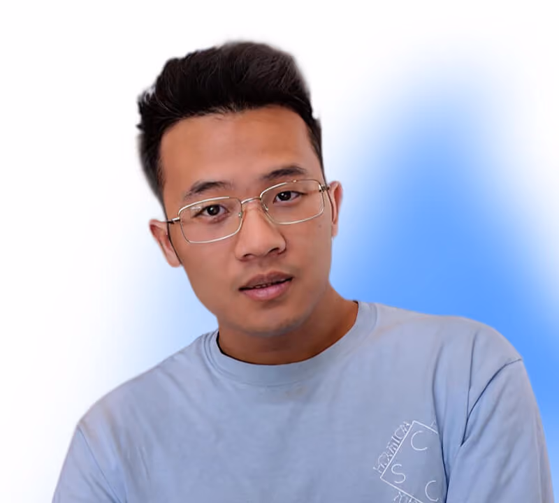 Man with short black hair wearing glasses and a light blue shirt against a white and blue background.