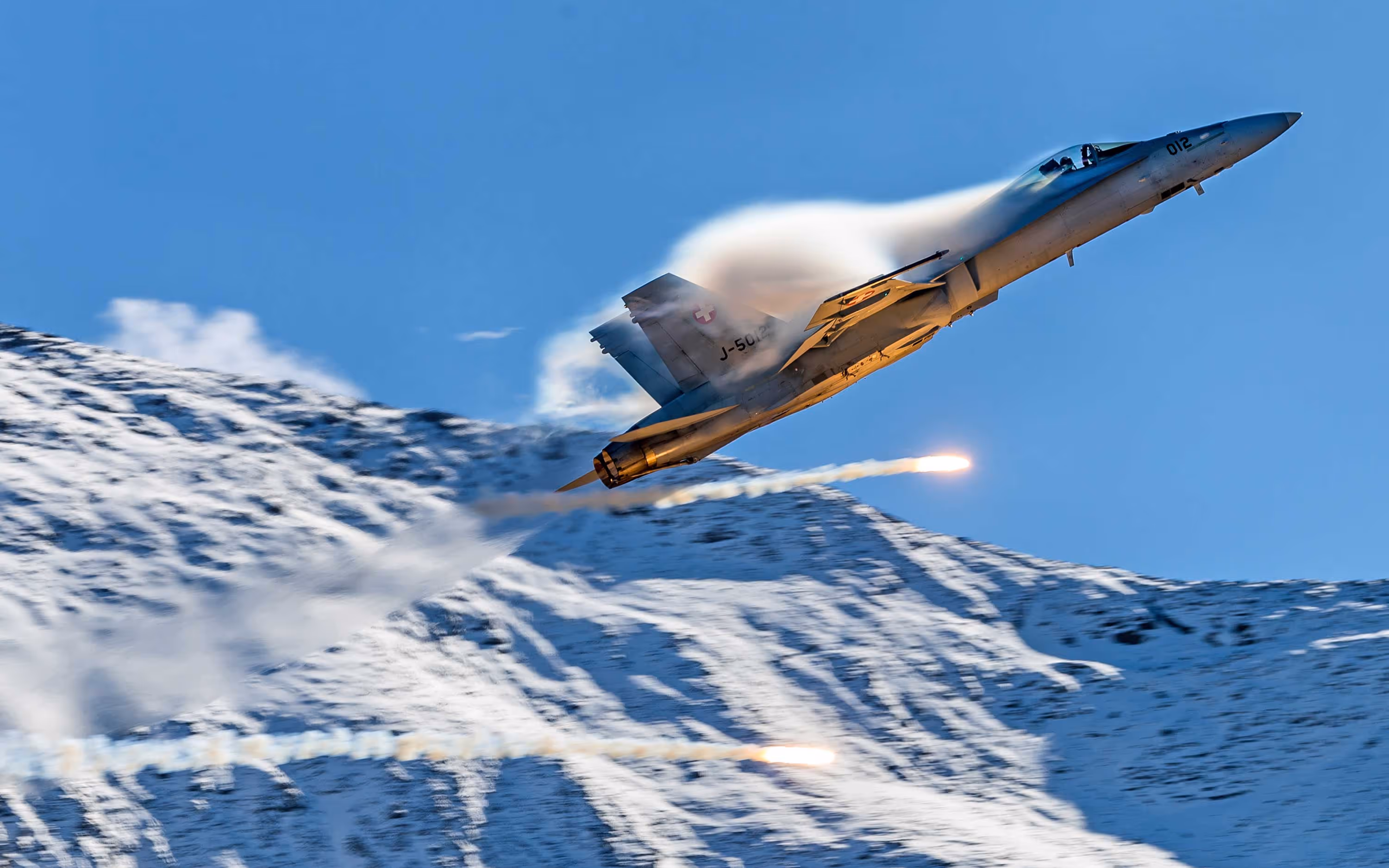 Swiss Air Force F/A-18 pulling vapor flying through the Swiss Alps, Axalp, Switzerland