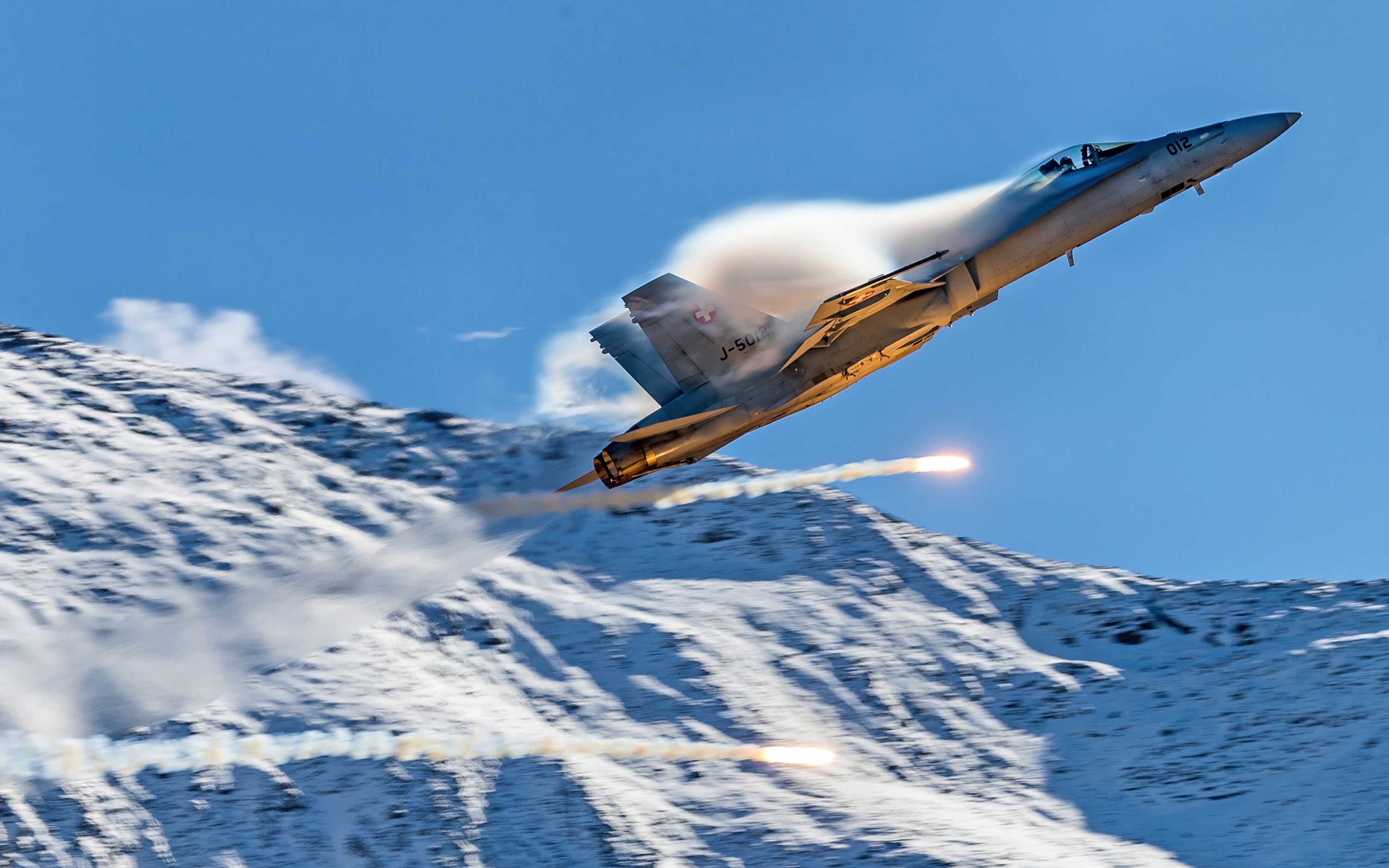 Swiss Air Force F/A-18 pulling vapor flying through the Swiss Alps, Axalp, Switzerland