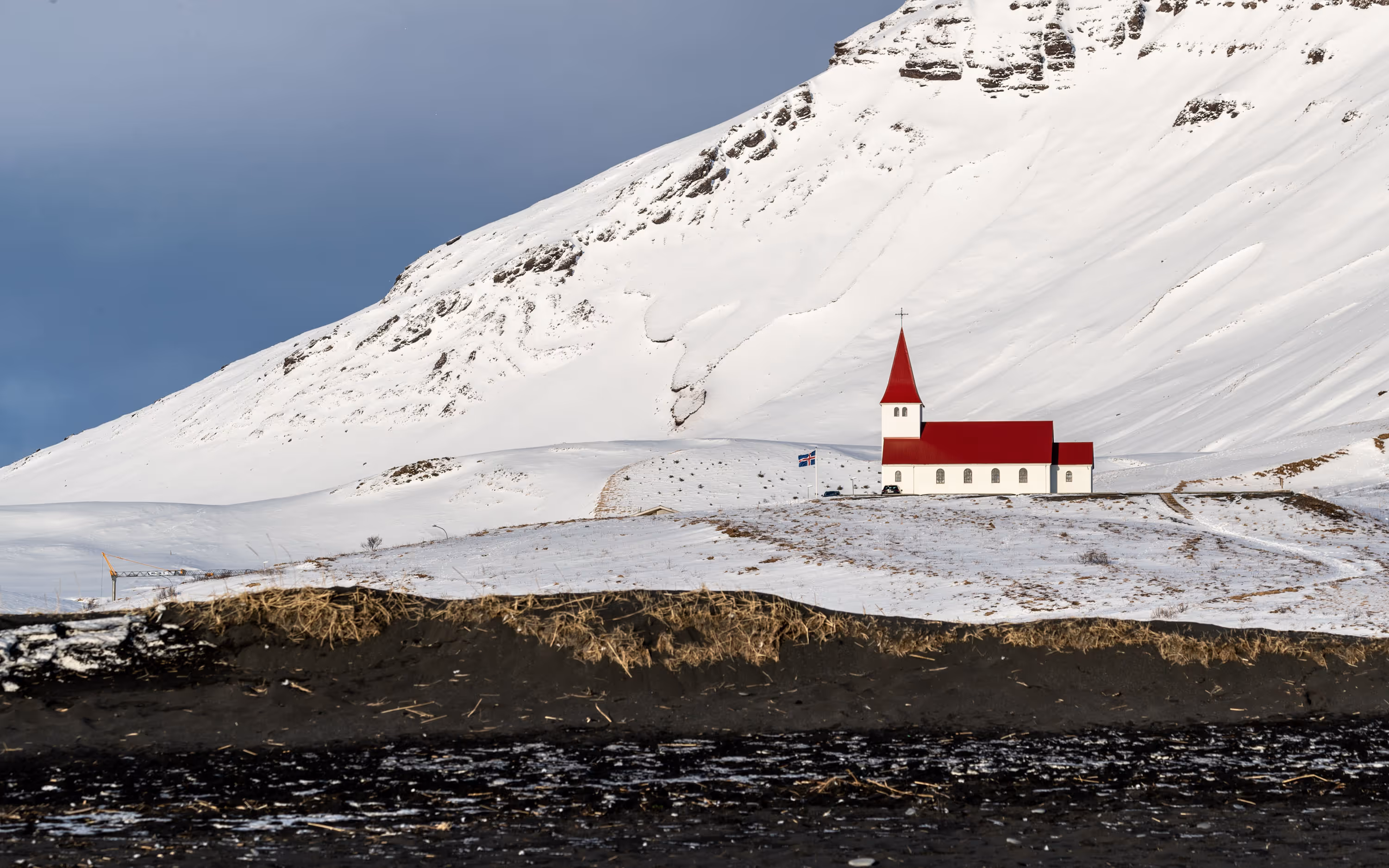 Church on a snowy hillside near a black sand beach, Vik, Iceland