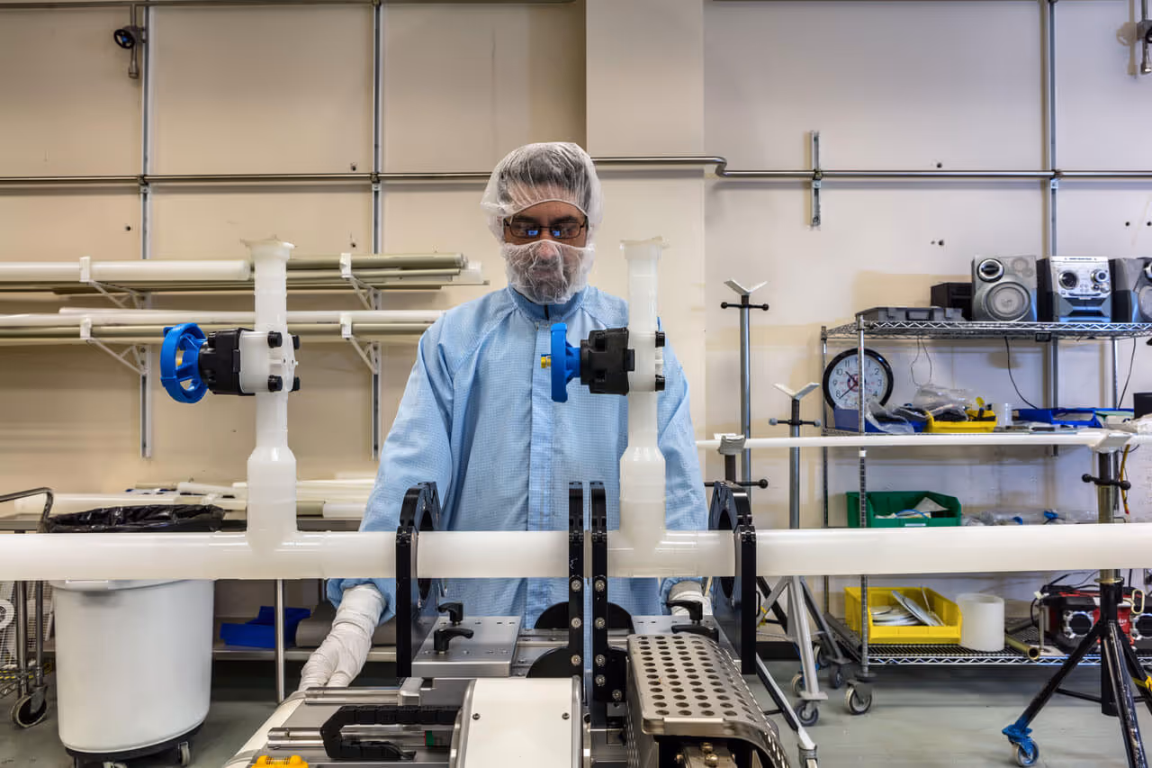 A worker wearing protective equipment fabricating custom plastic piping