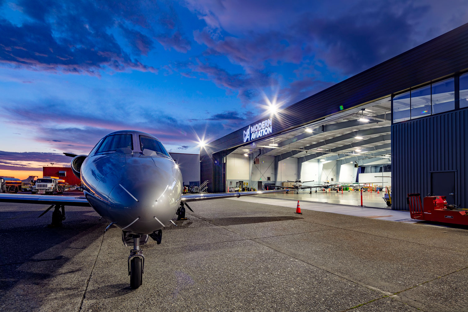A twilight architectural photo of business jet in front of a new aircraft hangar