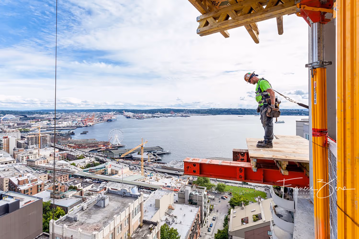 A construction worker peers over the edge of an under-construction skyscraper floor high above Seattle