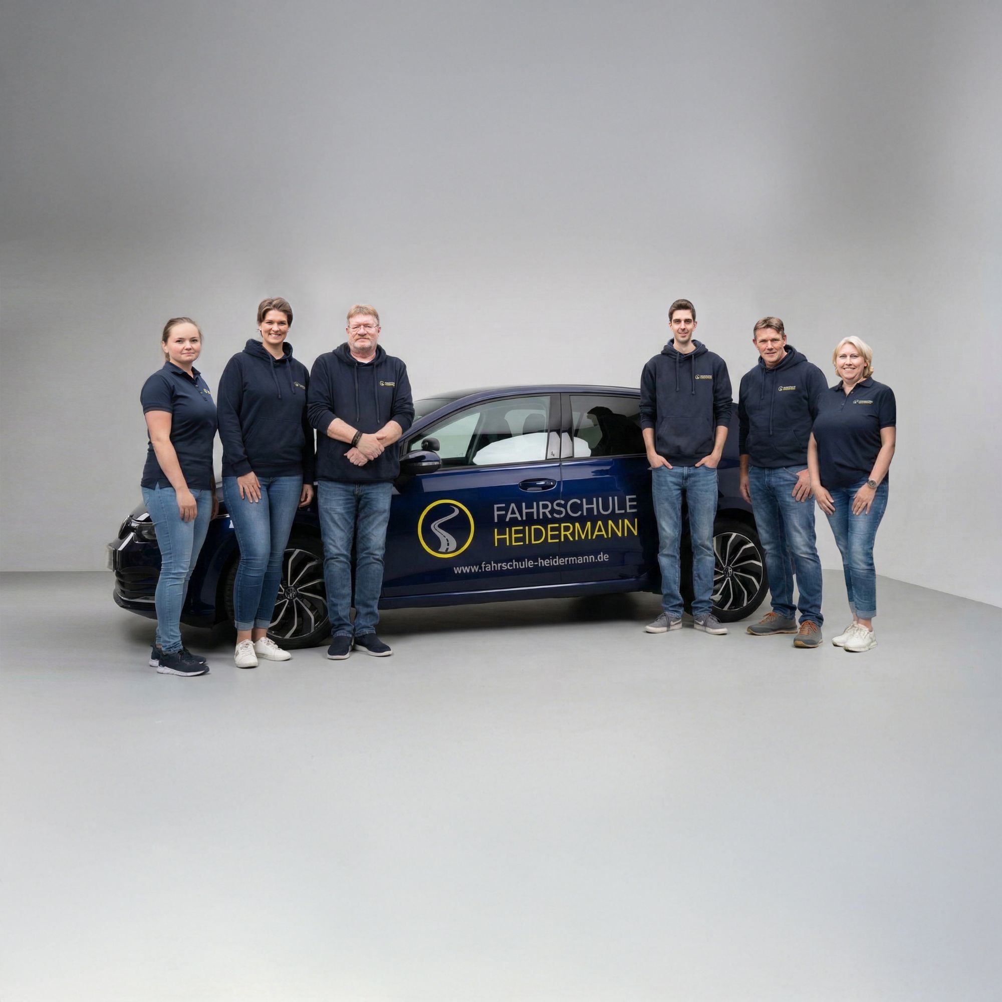 Teamfoto in einem Fotostudio mit einem Fahrschulwagen im Hintergrund