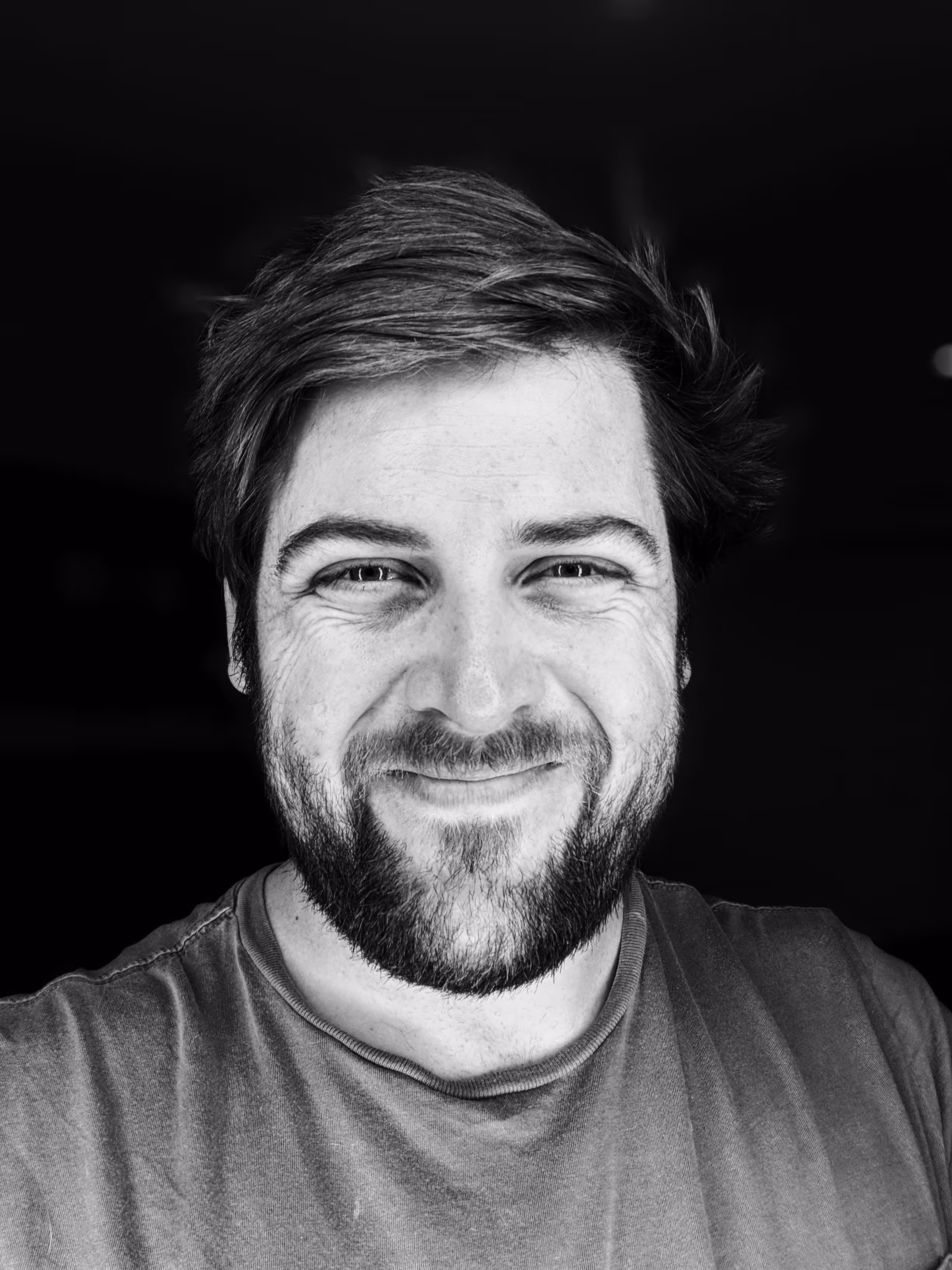 Black and white portrait of a smiling person with beard