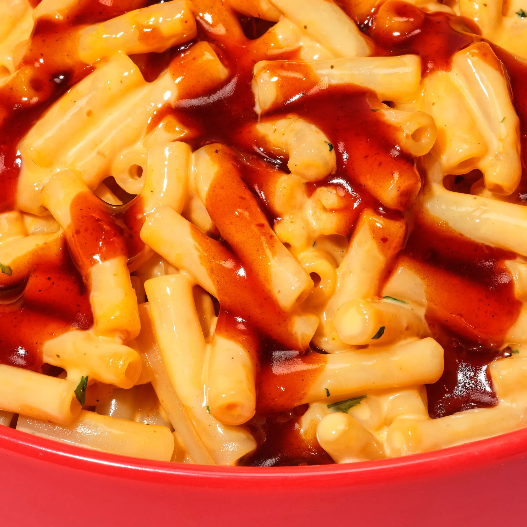 Close up of carbonara pasta with chilli sauce in a red bowl