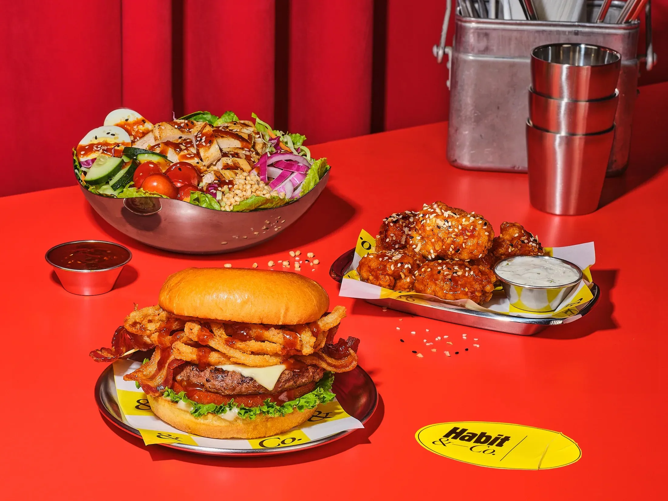 Table spread of a bacon cheeseburger, salad bowl and crispy chicken tenders