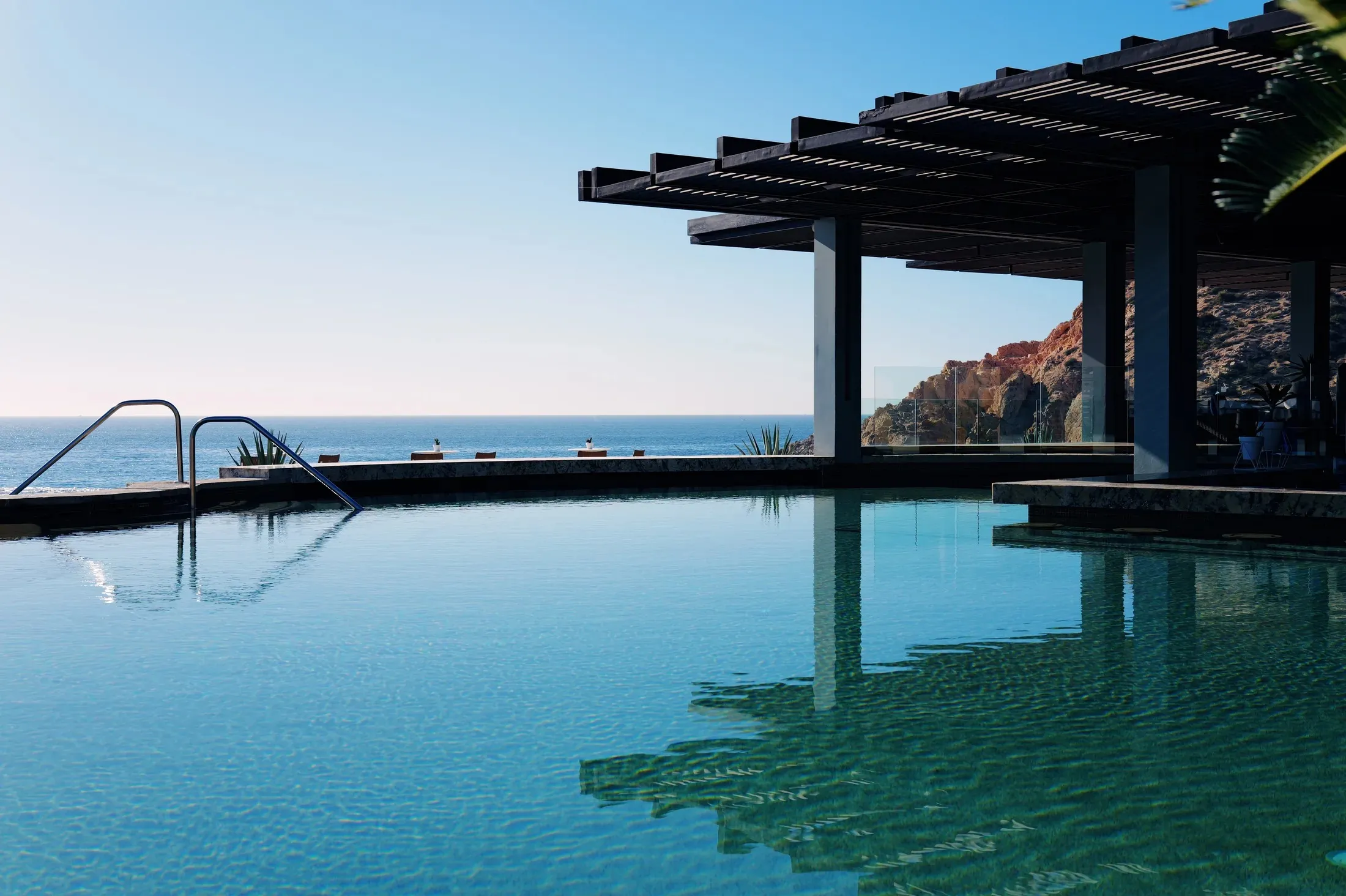 Infinity pool meeting the ocean beside a shaded pavilion at Montage Los Cabos