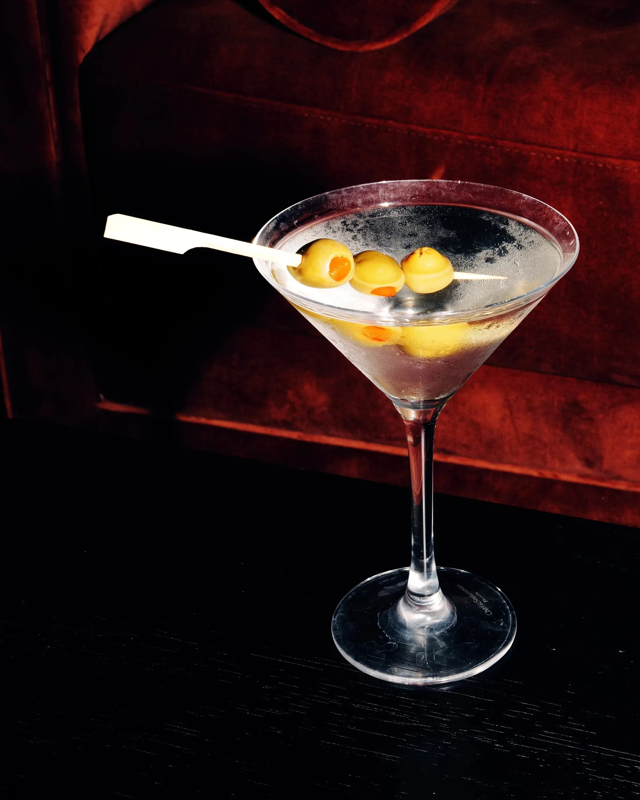 Martini with olives on a dark bar against red velvet, La Quinta Resort