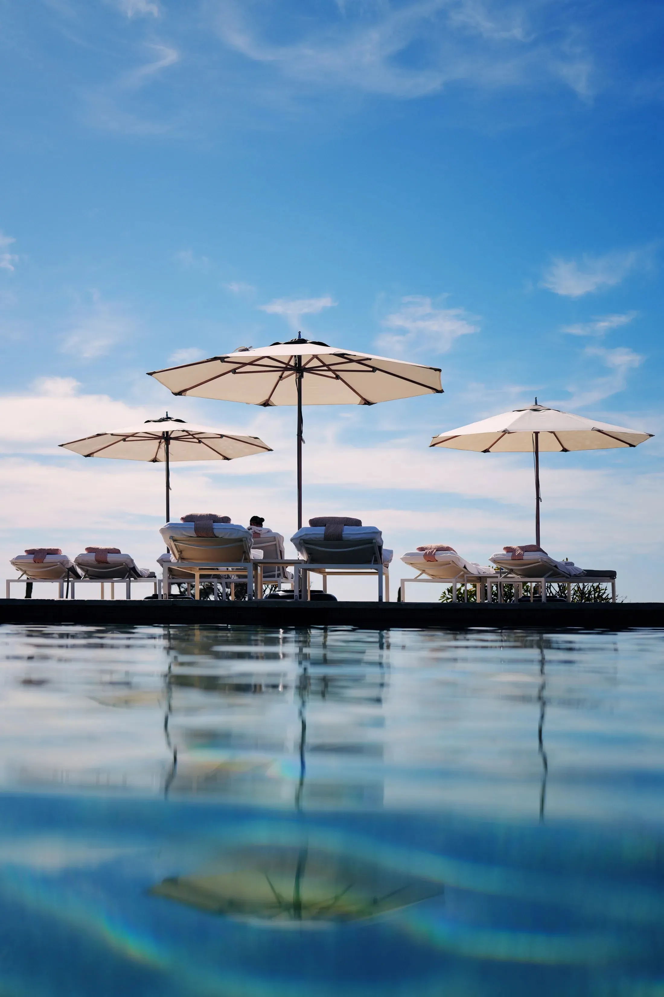 Poolside umbrellas and loungers reflected in still water at Montage Los Cabos