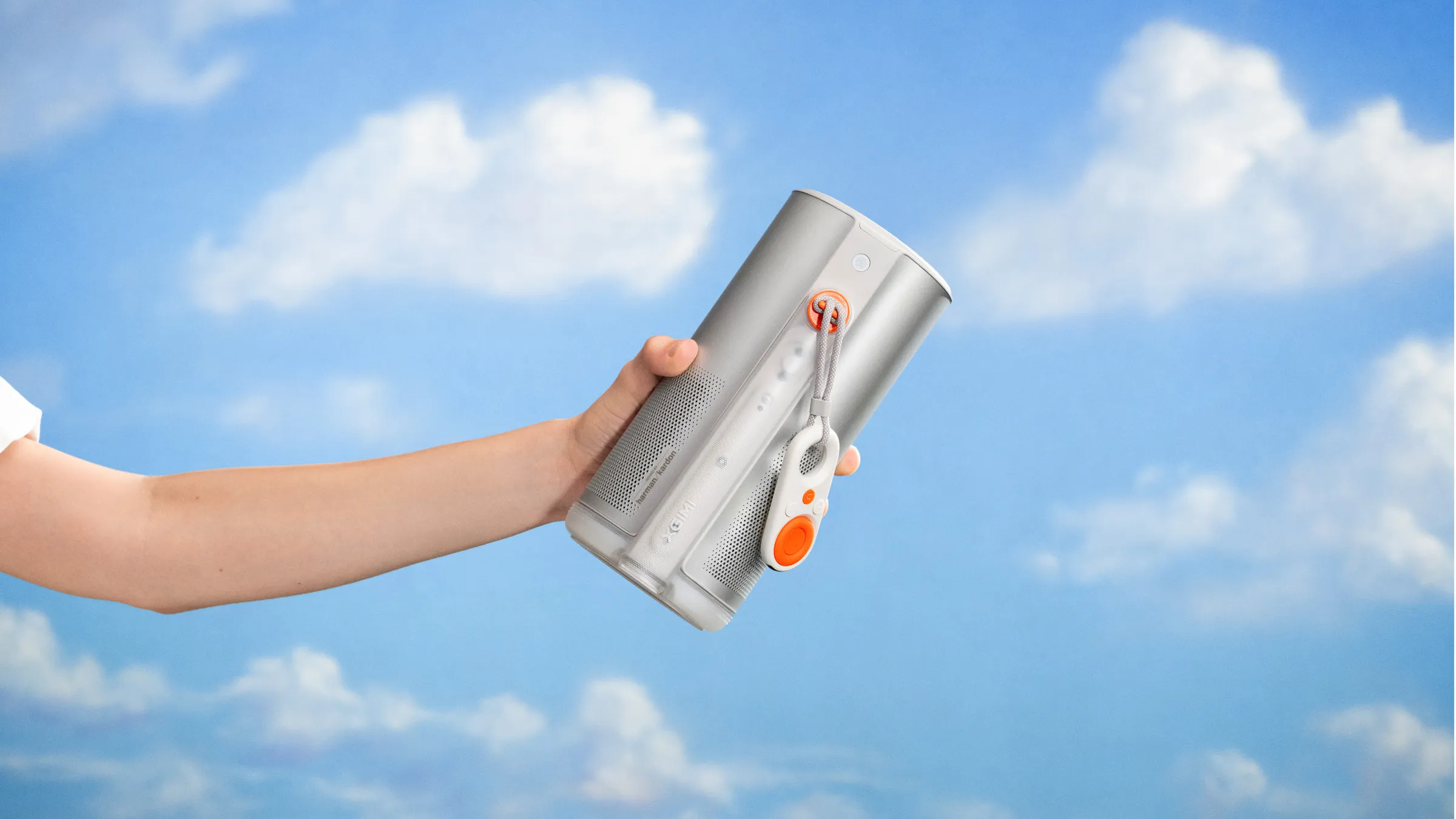 Hand holding an XGIMI MoGo projector against a blue sky with scattered clouds