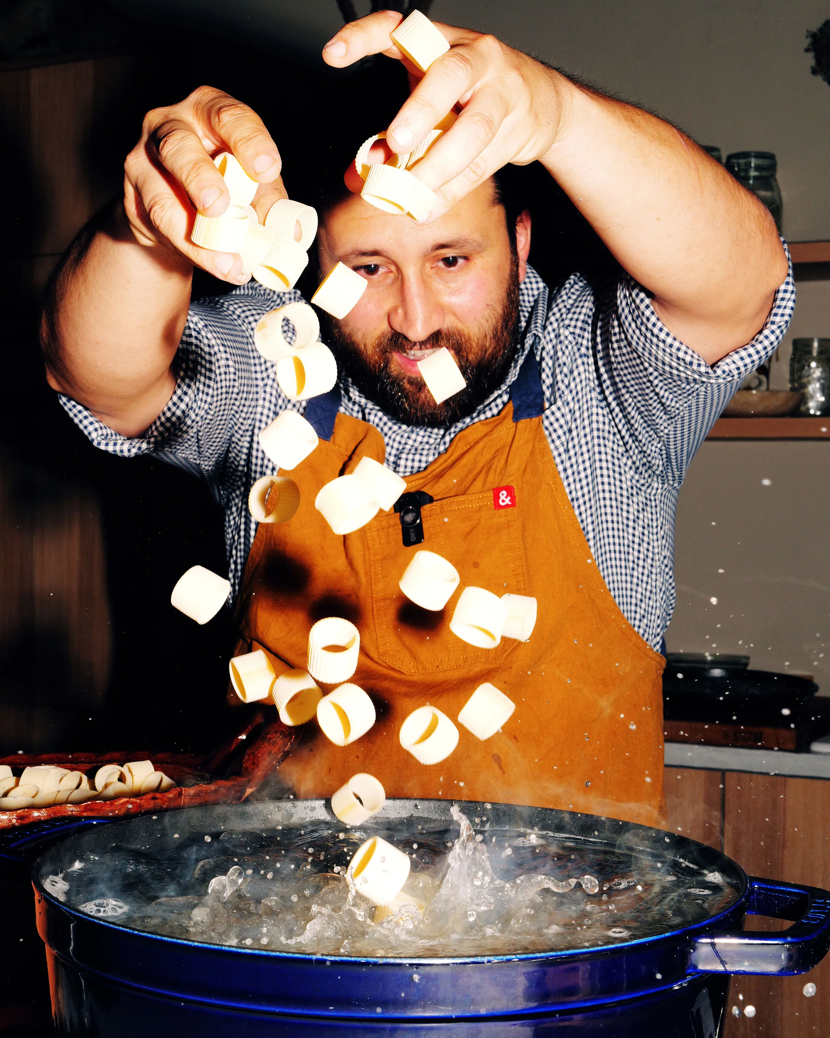 Bearded chef in a work apron dropping marshmallows into a steaming pot